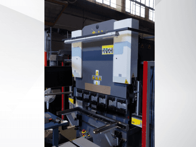 Press brake machine, front view. Features visible controls, safety stickers, and multiple die holders for precision bending.