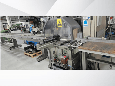 Industrial cutting machine from a side view, featuring a long conveyor, control panel, and safety warnings.